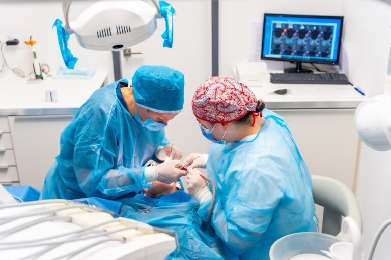 Female dentists in blue scrubs performing a complicated operation on a female patient sucking blood